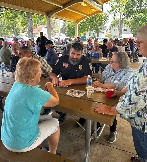 Police Chief sitting at a picnic table talking with 3 females